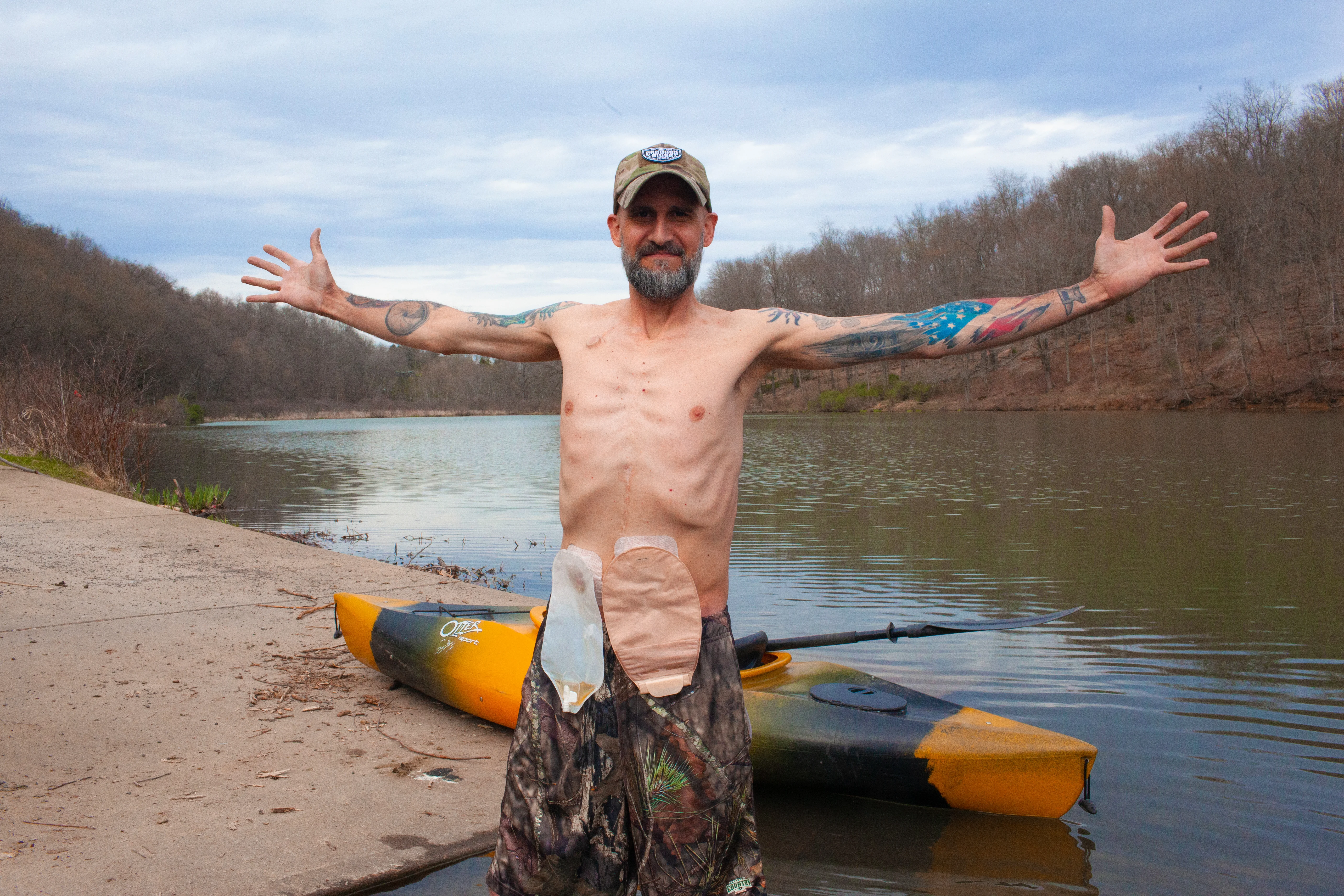 a man standing in front of a lake with his arms out